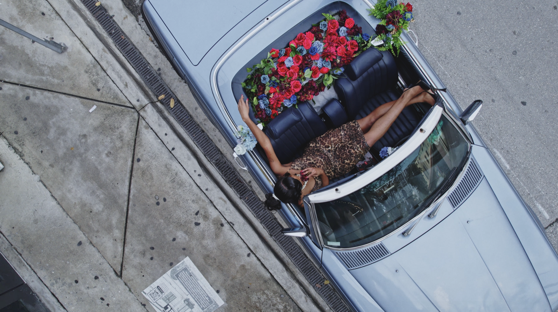 A woman lying in a flower-filled convertible