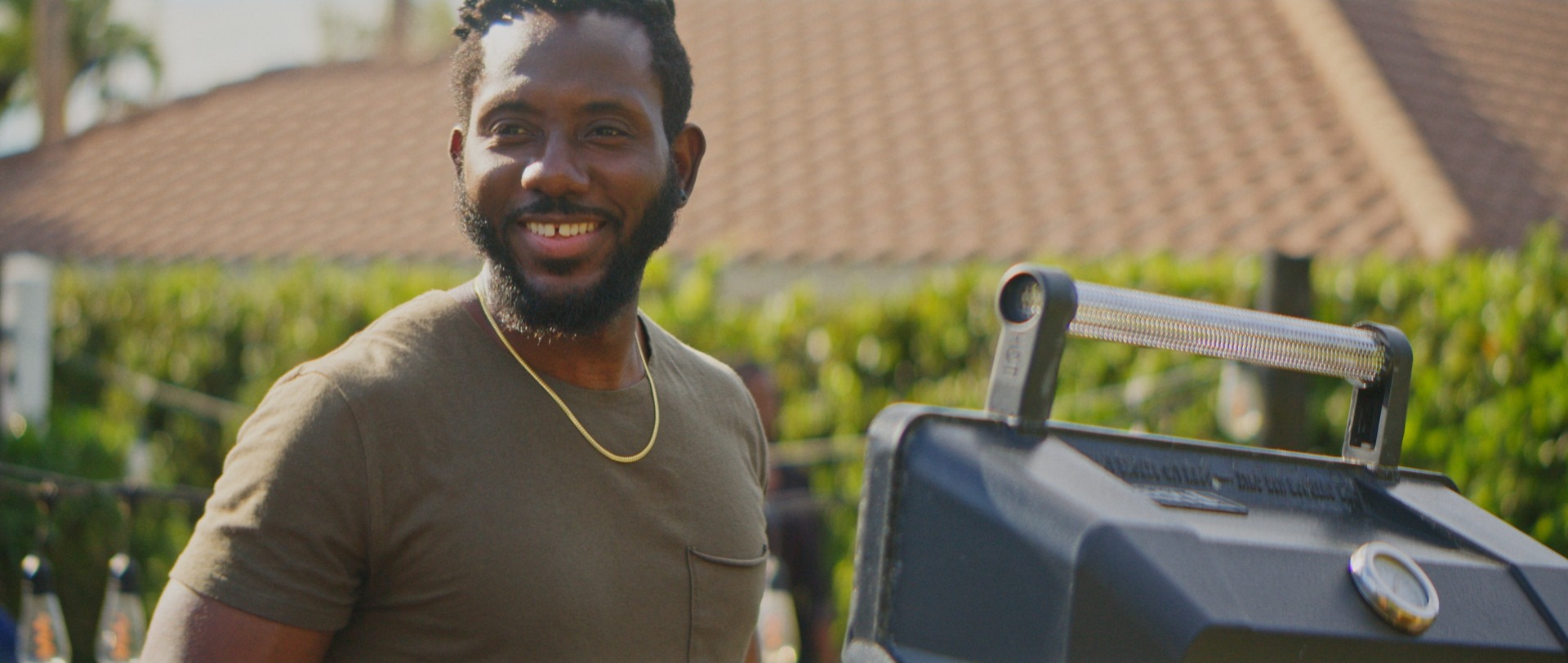 A man beside a grill in a backyard
