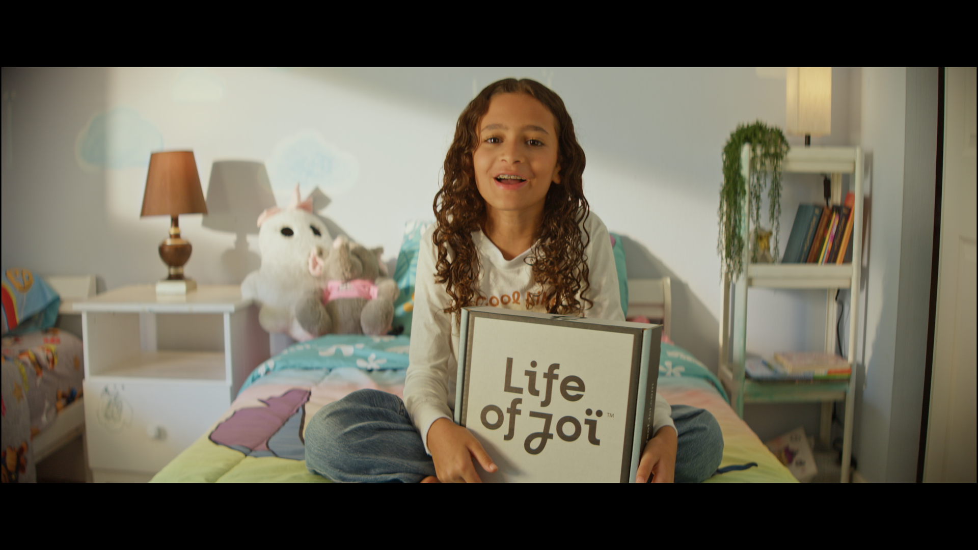 A girl holding a box on her bed