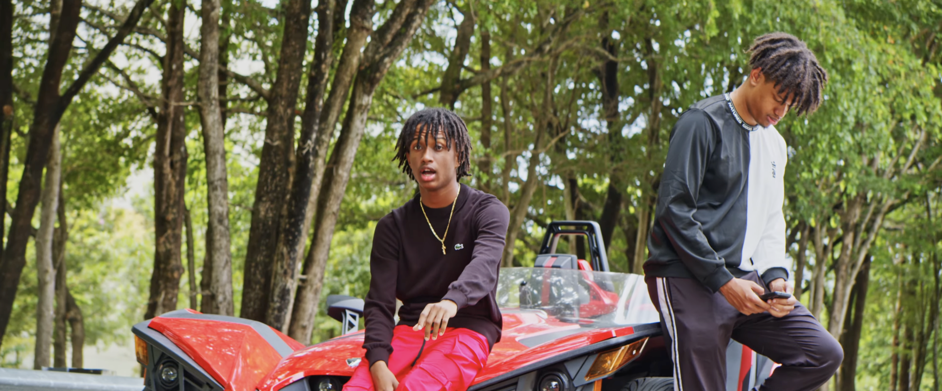 Two men beside a red off-road vehicle
