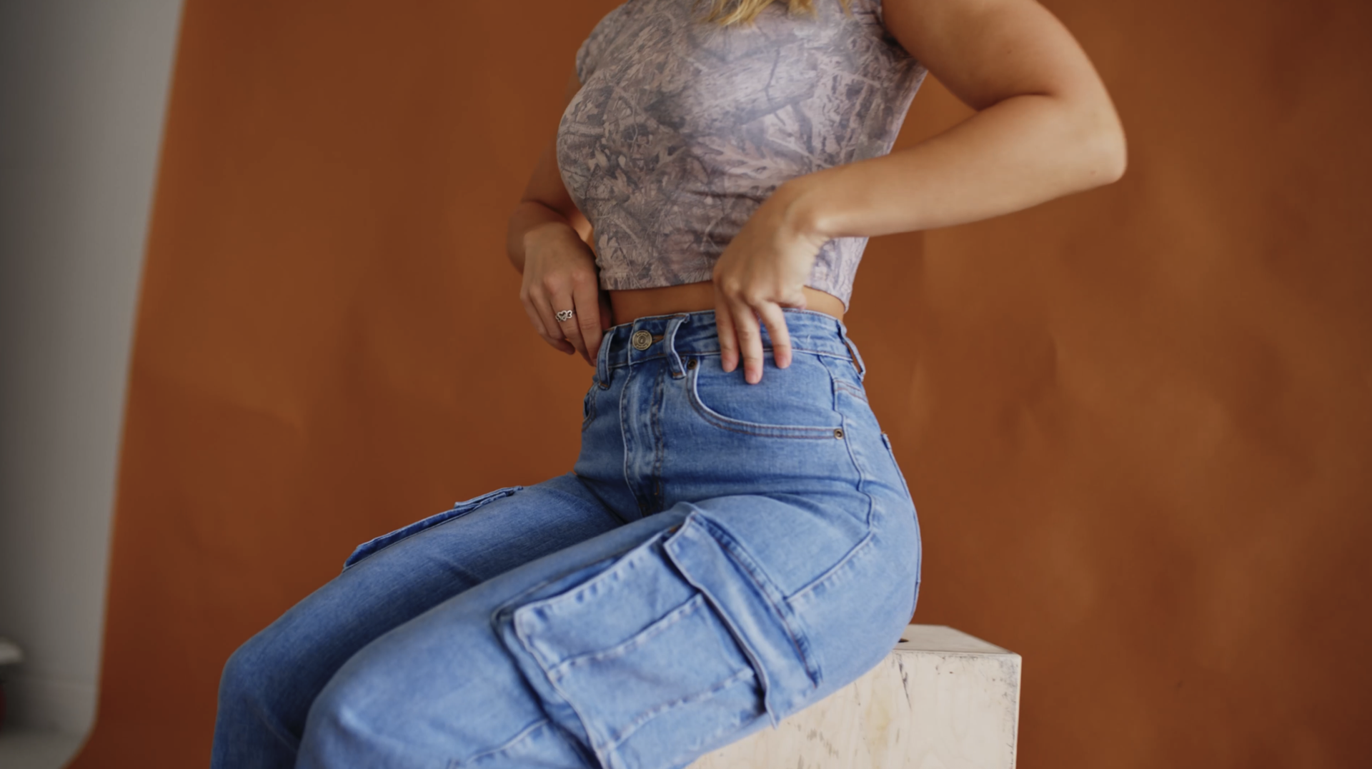 A woman in cargo jeans against an orange backdrop