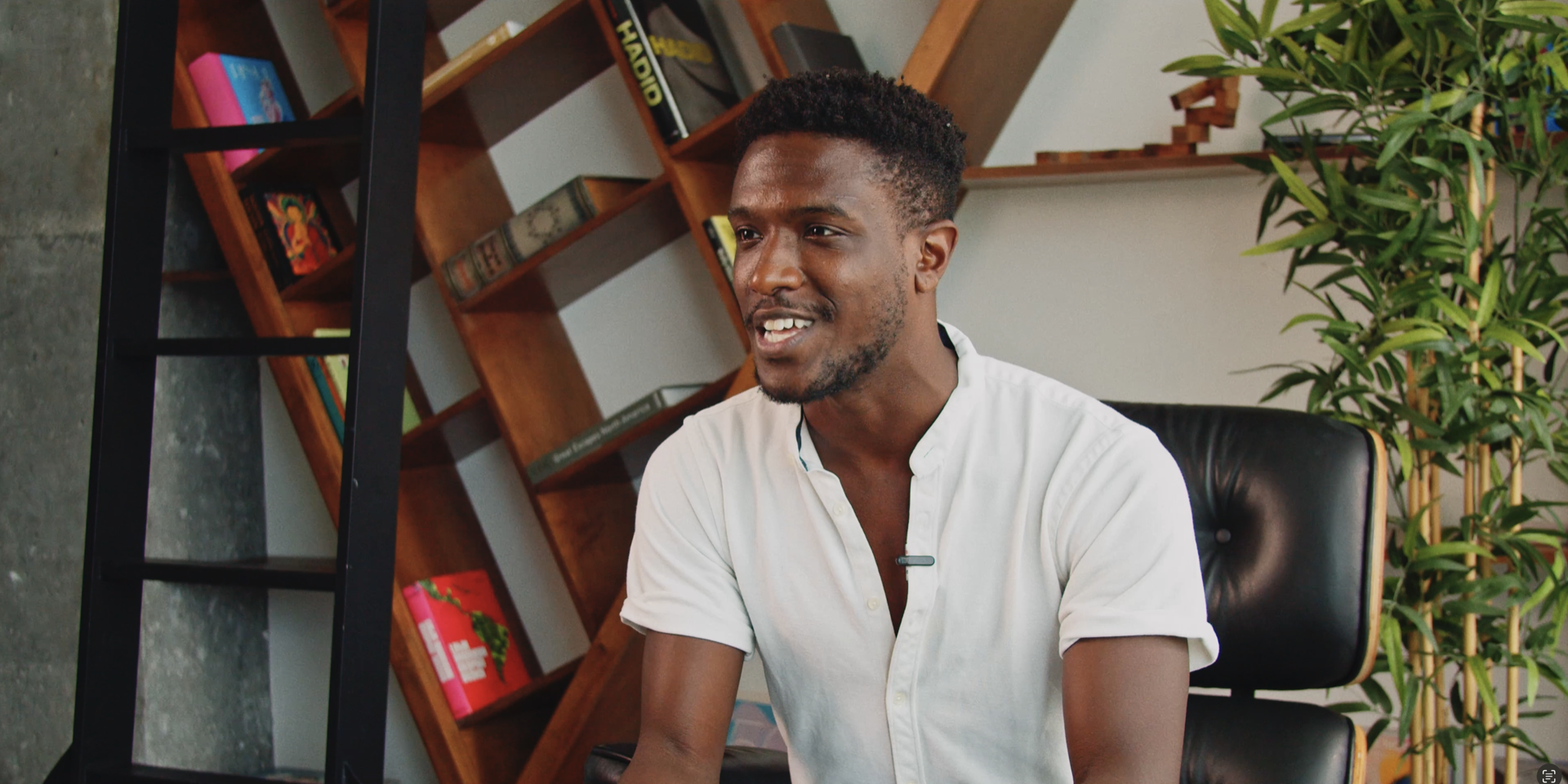 A man seated for an interview by a bookshelf