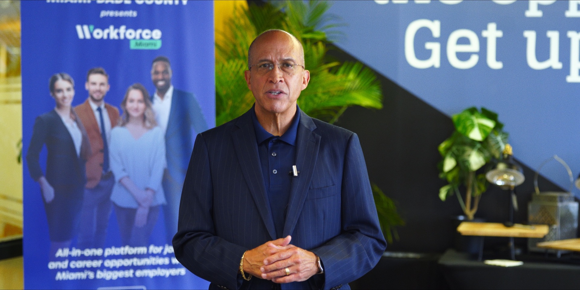 A man speaking in front of a Miami-Dade County banner